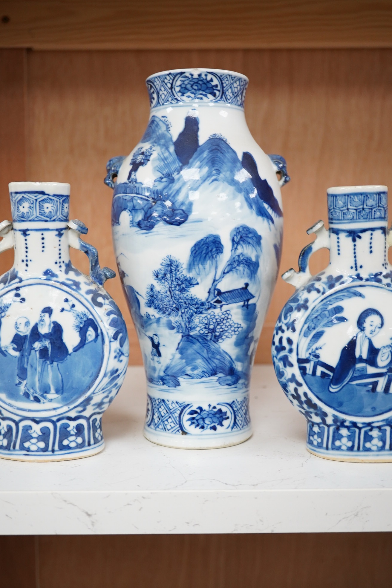 Late 19th century Chinese vases; pair of small Chinese blue and white moon flasks and a larger Chinese blue and white landscape vase, larger vase 22cm high. Condition - one moon flask handle restored, other items fair